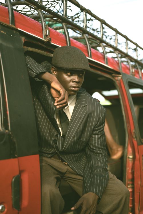 Free Man in a vintage striped suit and hat leaning out of a retro red van, conveying a sense of travel and style. Stock Photo