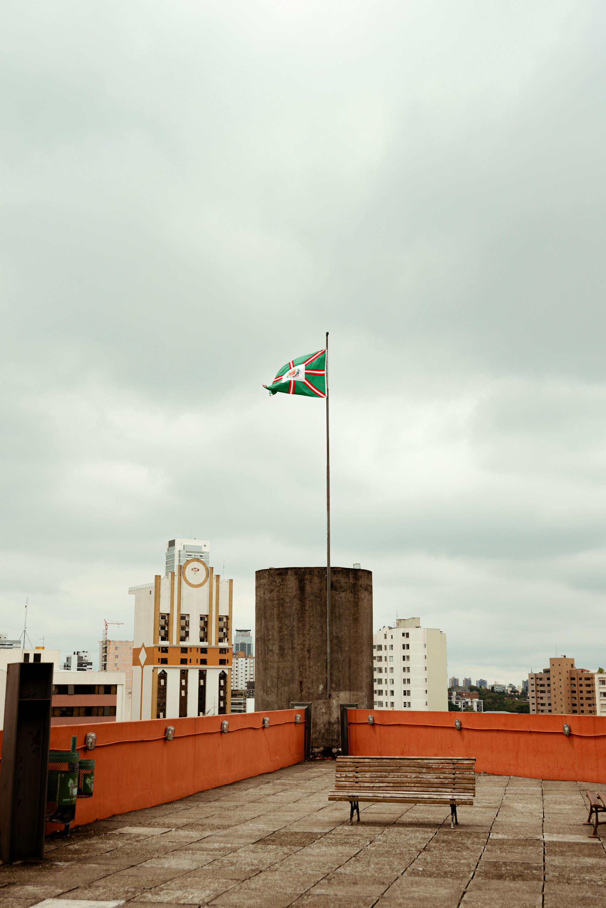 在多云的天空下，库里蒂巴的屋顶全景展现无遗，旗杆矗立其间，城市景观一览无余
