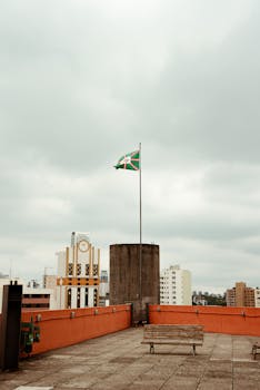 在多云的天空下，库里蒂巴的屋顶全景展现无遗，旗杆矗立其间，城市景观一览无余