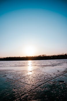 A serene winter sunset over a frozen lake in Langfang, Hebei, China.