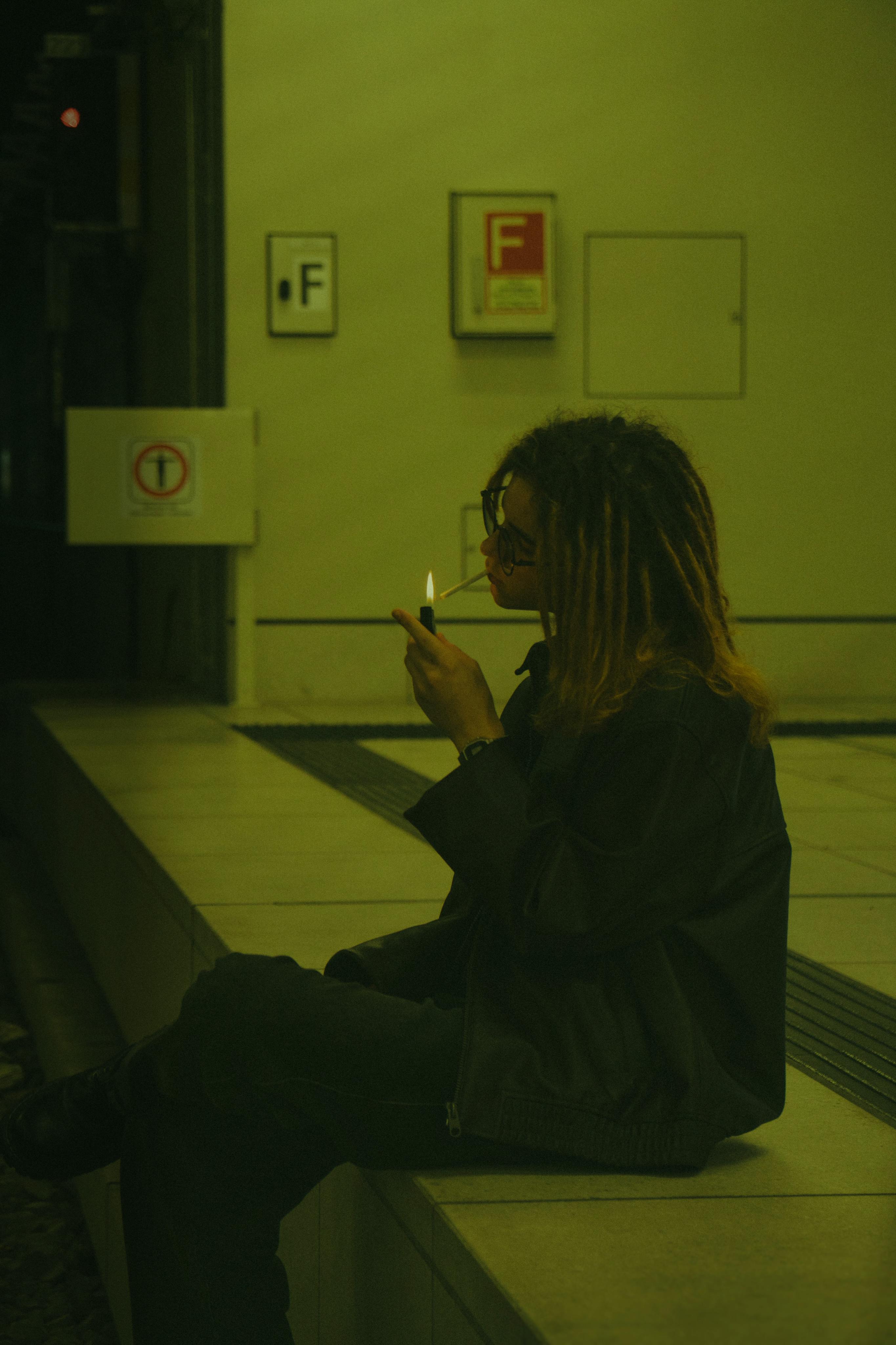 Free Silhouette of a person lighting a cigarette in a dimly lit subway station. Stock Photo