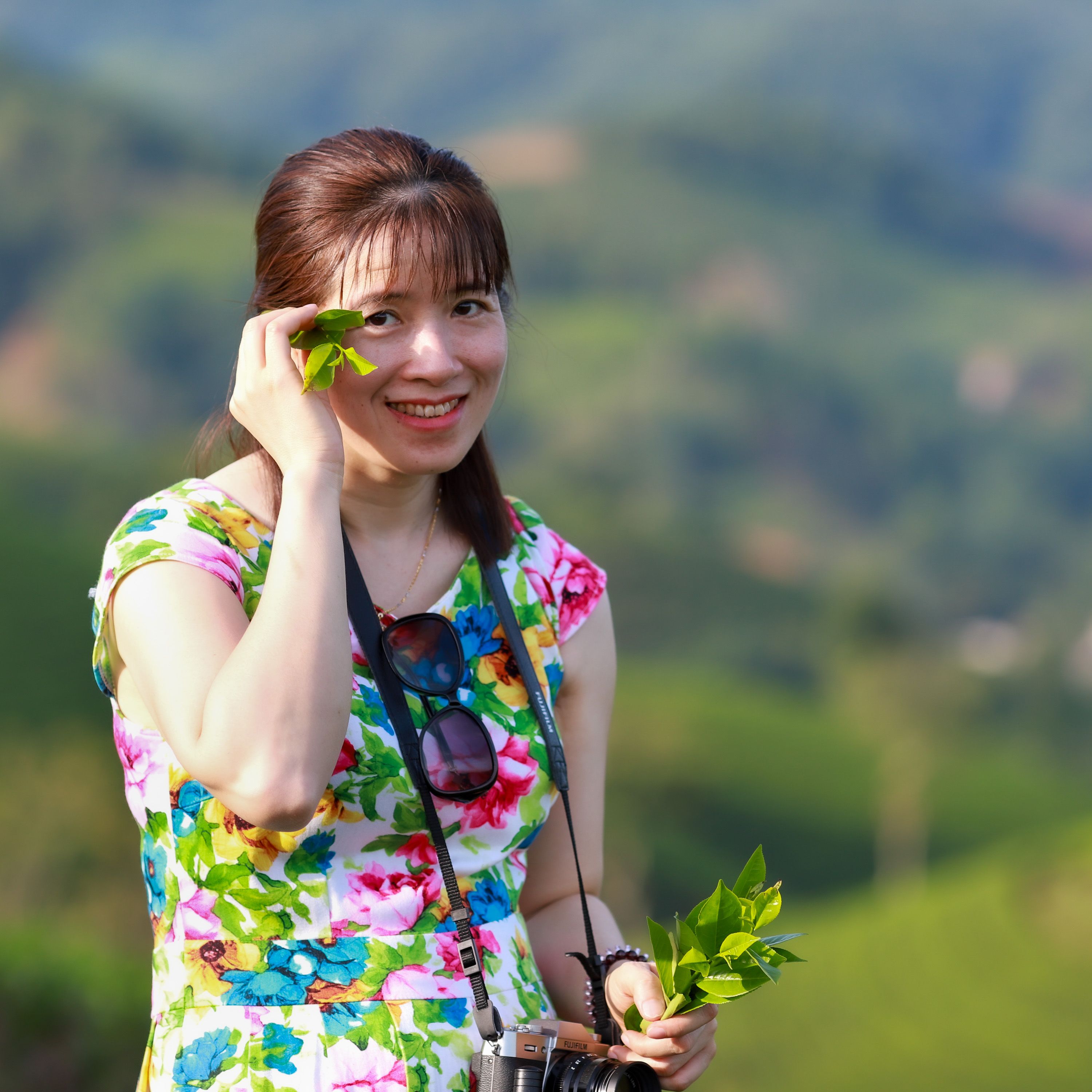 A woman in a floral dress enjoys a sunny day in the tea fields of Phú Thọ, Vietnam.