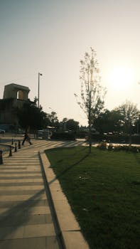 日落时分，宁静的城市街景中，草地公园附近有一个孤独的人行横道