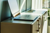 A laptop on a sunlit office cabinet, ideal for professional or corporate contexts.