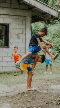 Group of children playing leapfrog outdoors on a summer day in a rural setting.