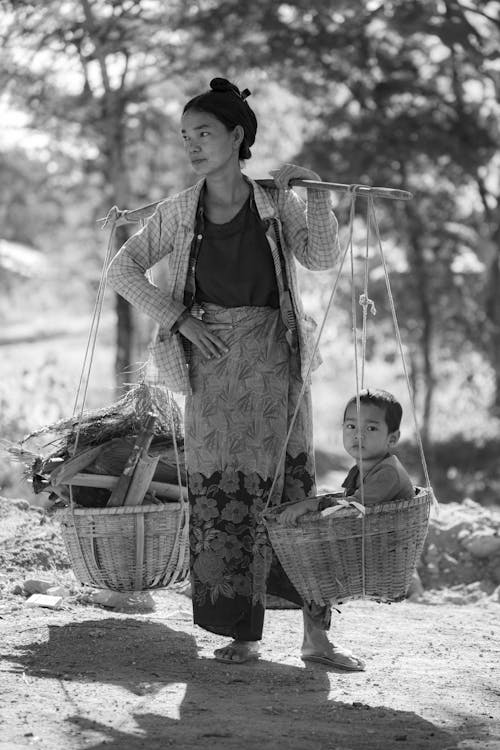 Femme Portant Des Paniers Avec Enfant Et Bois