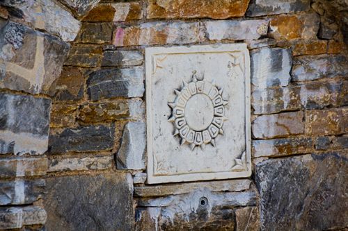 Free Decorative stone wall featuring a sun design with intricate details symbolizing historical craftsmanship. Stock Photo