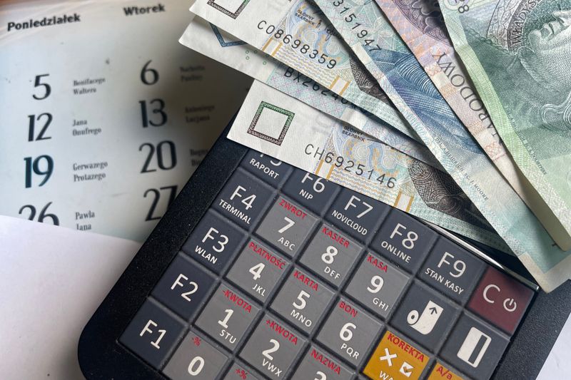Close-up of Polish Zloty banknotes on a calculator with a calendar in the background.