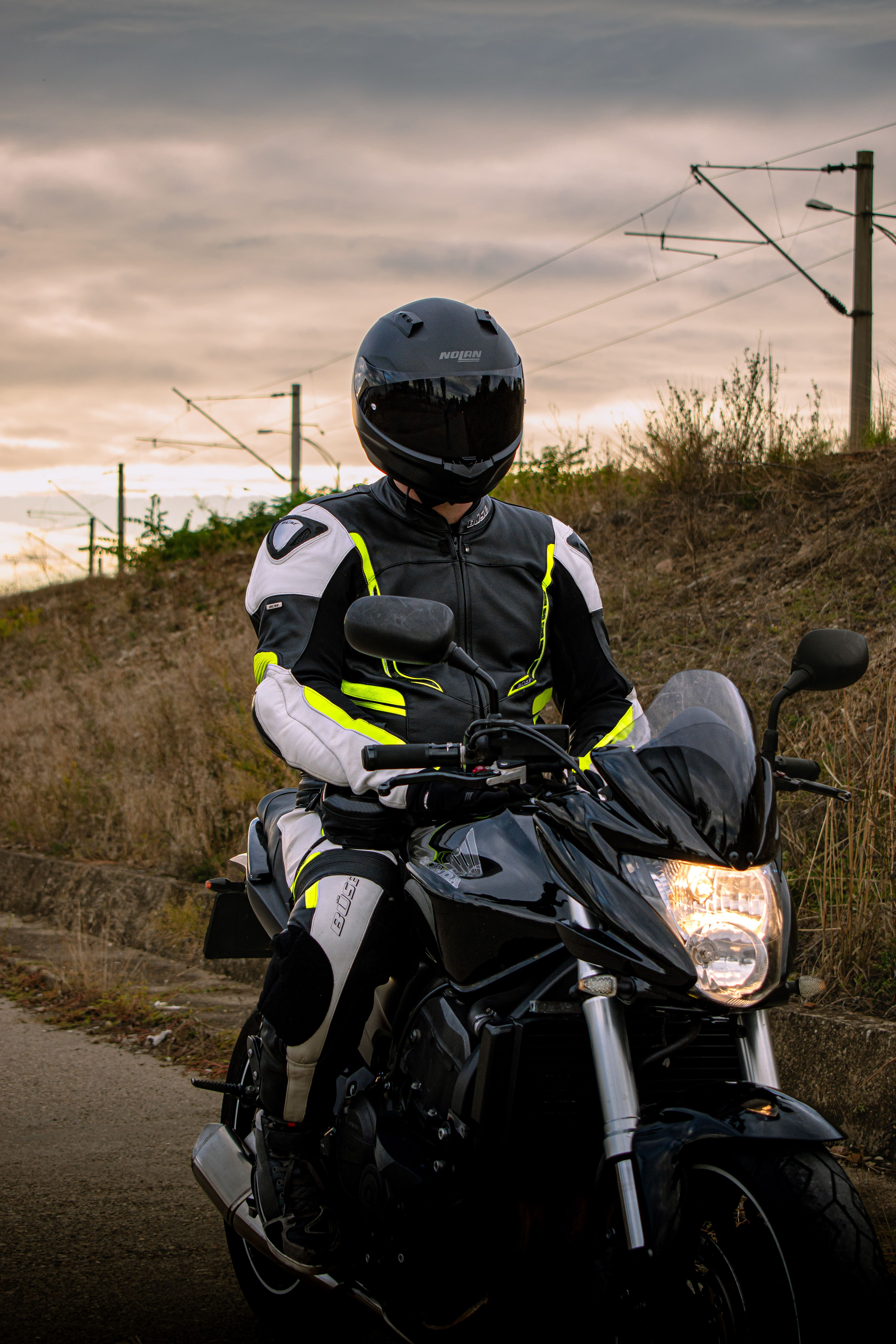 Rider on black sport motorcycle with gear under cloudy sky.