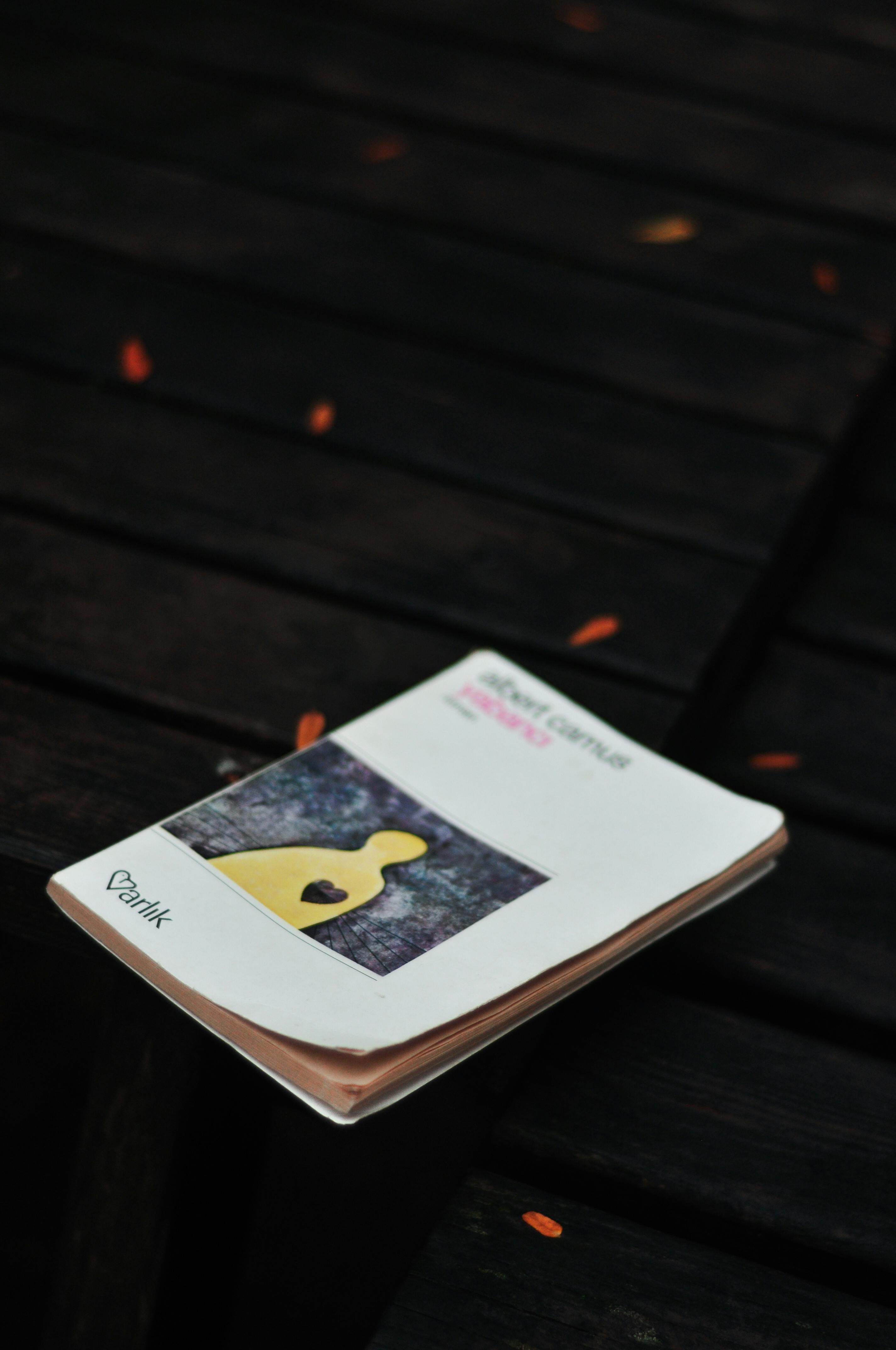 grátis Um caderno artístico repousa sobre uma superfície de madeira escura com uma figura amarela com um símbolo de coração. Foto profissional