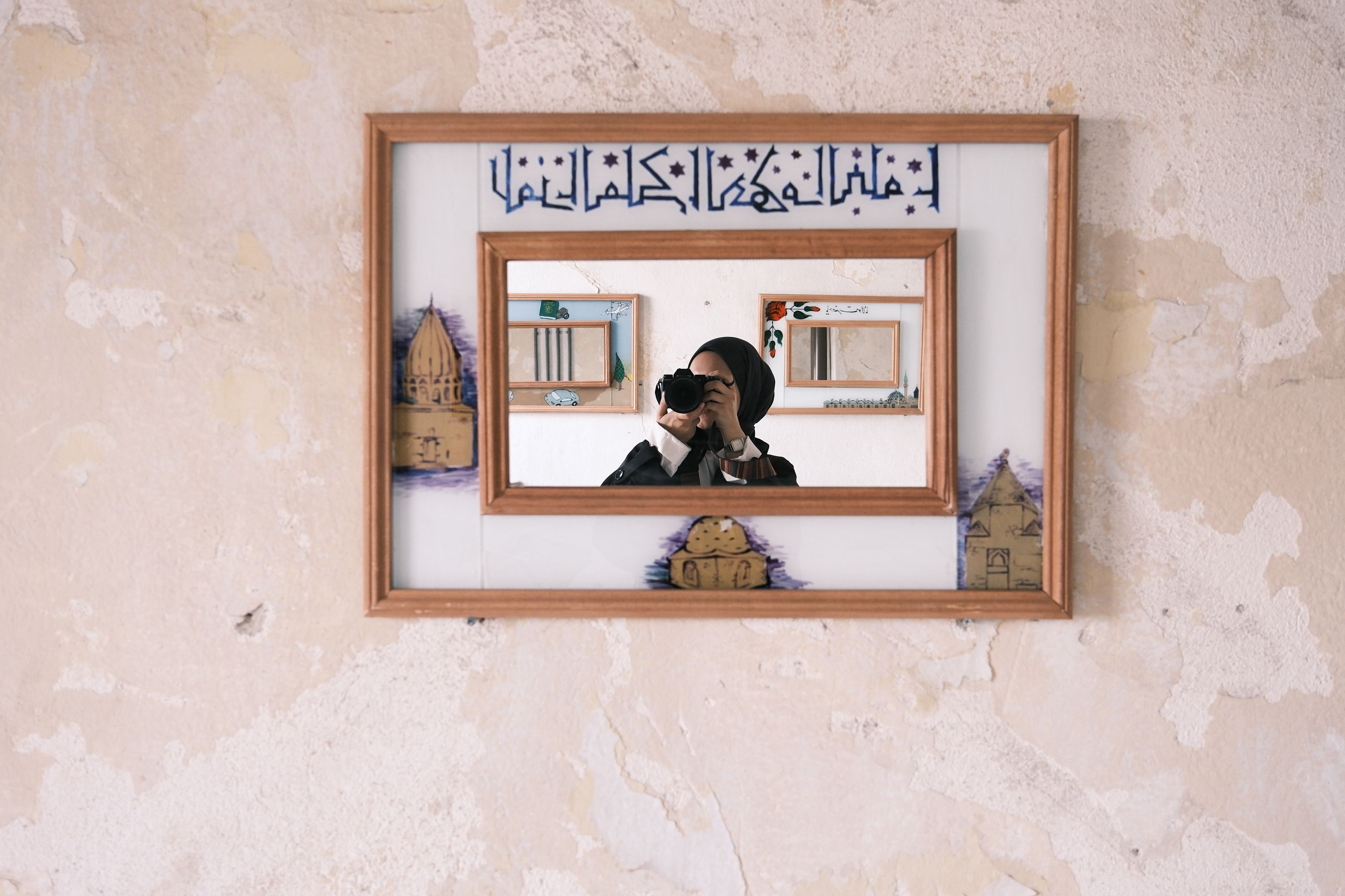 Photographer captures reflection in a decorative mirror with Arabic calligraphy, Konya, Türkiye.