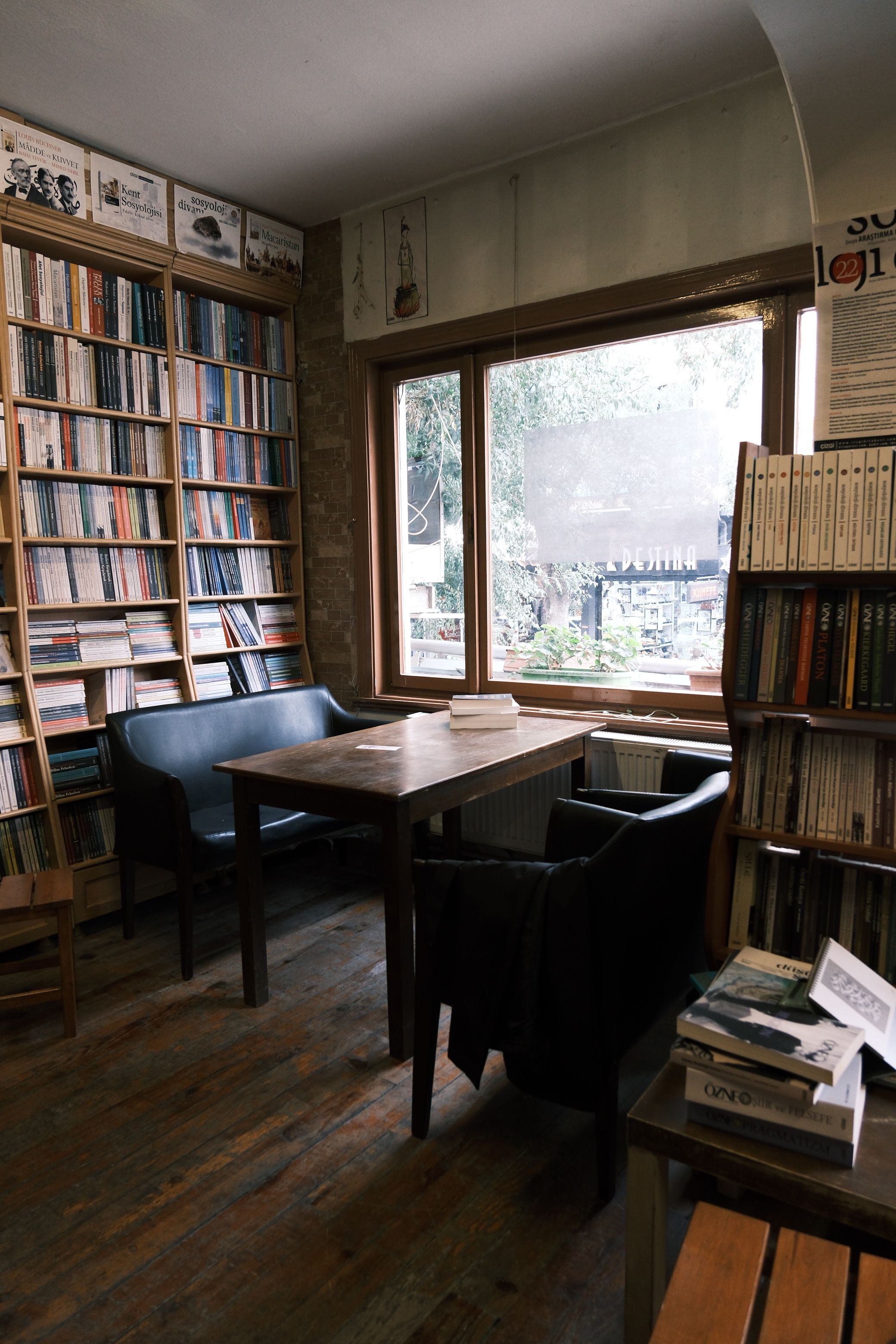 A quiet bookshop corner with armchairs beside a tall window