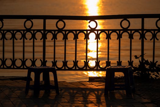 Silhouetted chairs by the West Lake in Hà Nội at sunset, reflecting golden light.