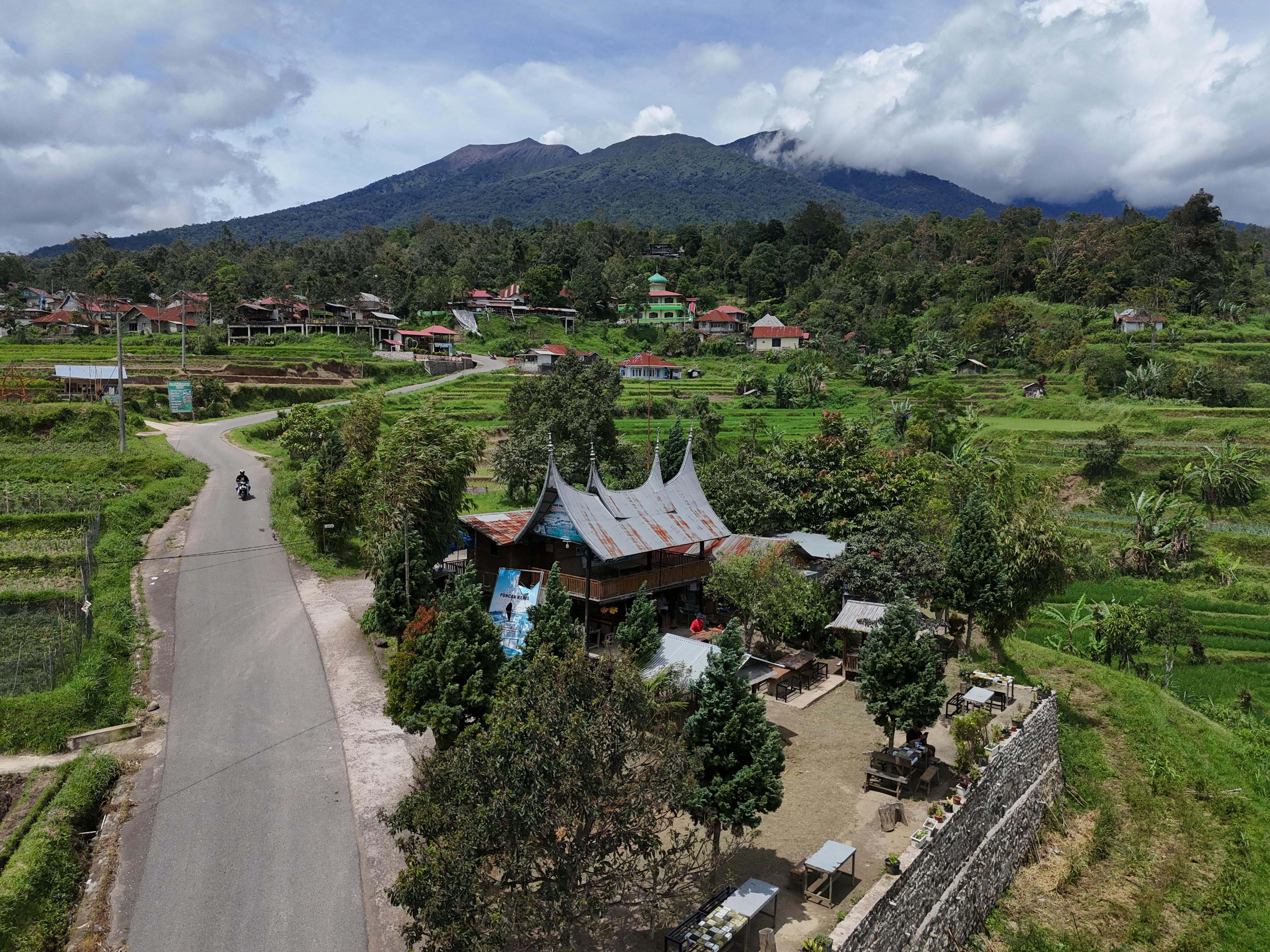 Aerial view capturing a traditional Minangkabau village amidst lush greenery in West Sumatra, Indonesia.