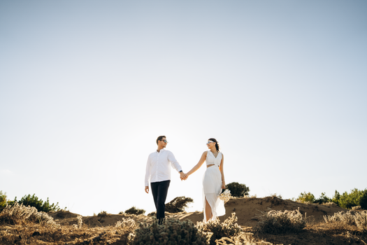 A couple holding hands while walking on a sunny beach in Antalya, Türkiye.