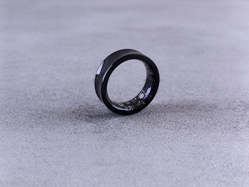 What Research Reveals About Oura Ring Sleep Staging Accuracy A modern black smart ring with visible circuitry resting on a textured concrete surface.