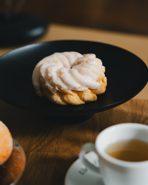 Free Close-up of a fresh iced spritzkuchen on a black plate with a cup of tea. Stock Photo