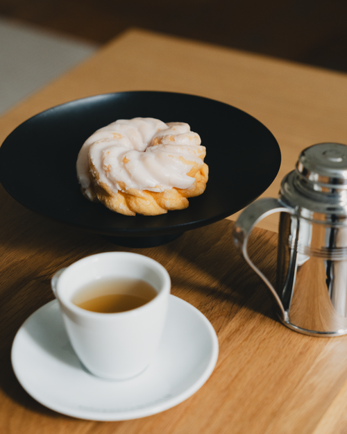 Free Appetizing iced pastry on a black plate beside a tea cup and shiny teapot. Stock Photo