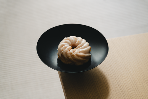 Free Spritzkuchen donut in black bowl on wooden table, soft light. Stock Photo