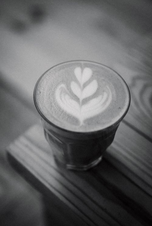 Free Elegant black and white latte art design on a glass cup on a wooden table. Stock Photo