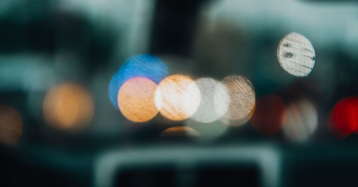 Blurred city lights through a rainy car window creating a bokeh effect.