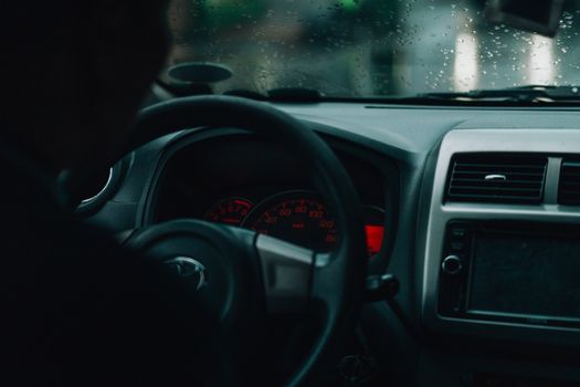 Interior car view with dashboard and raindrops, focusing on driving in rainy conditions.