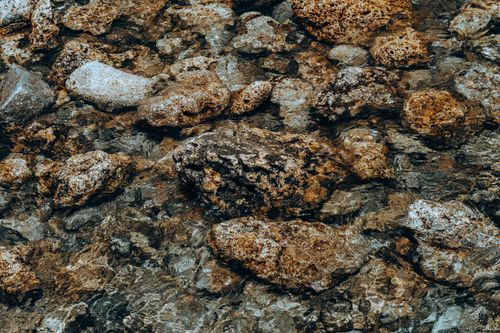 Free A serene view of natural riverbed rocks visible through clear, flowing water. Stock Photo