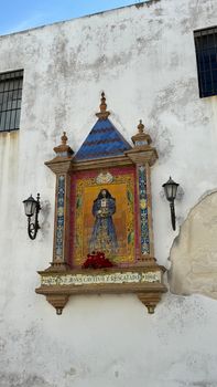 Ceramic tile depicting religious icon on weathered building wall in Cádiz, Spain.