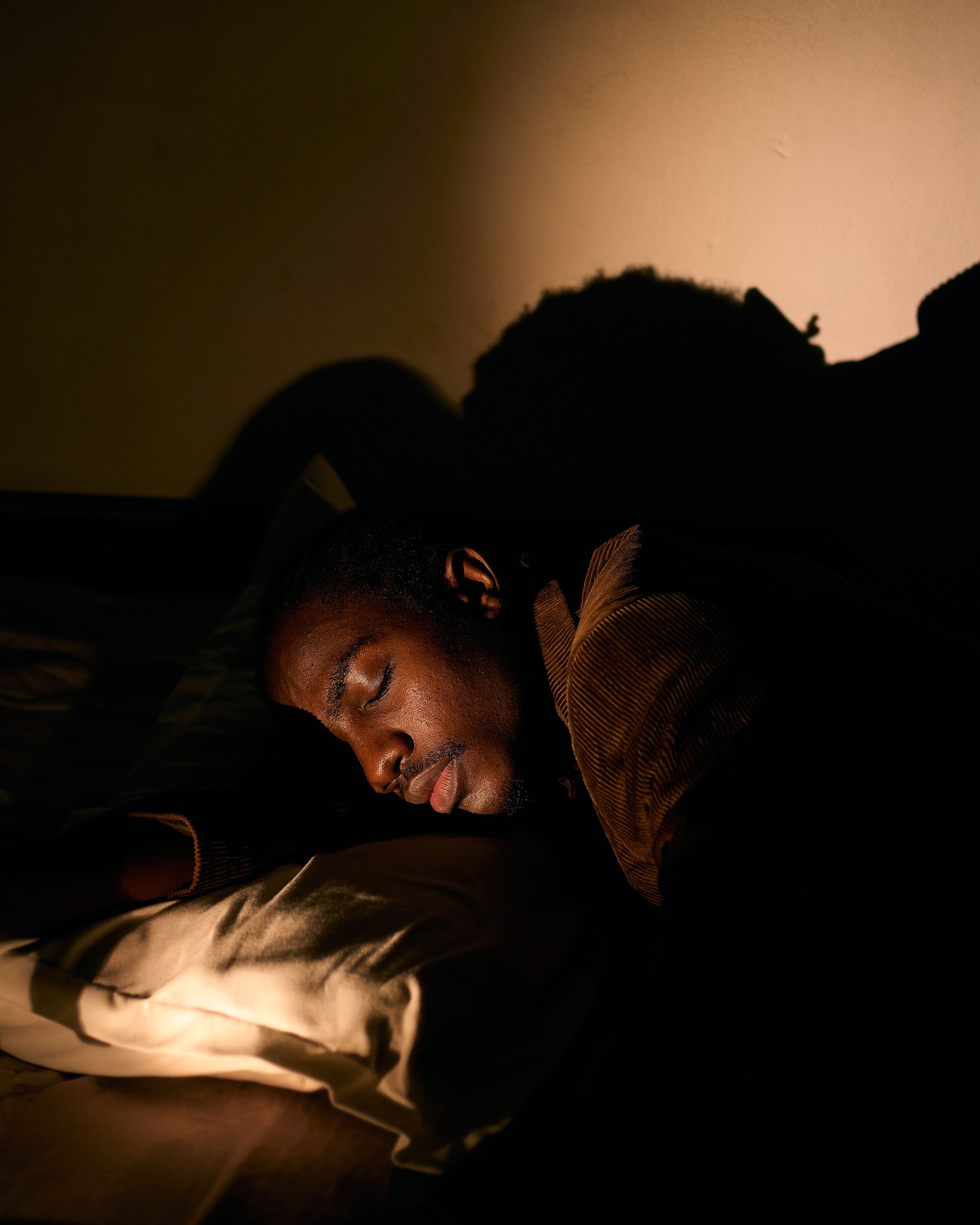 A man resting on a pillow in a dimly lit room, creating a serene and moody atmosphere.