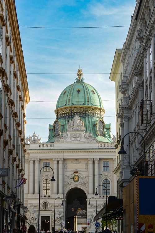 Free The beautiful green dome of Hofburg Palace seen from a Vienna street, framed by historic architecture. Stock Photo