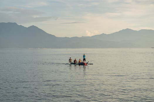 A group of adults kayaking on a calm lake with scenic mountains in the background at sunset.