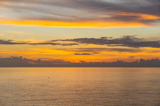 A serene ocean sunset with vibrant orange and yellow hues reflecting on the water.