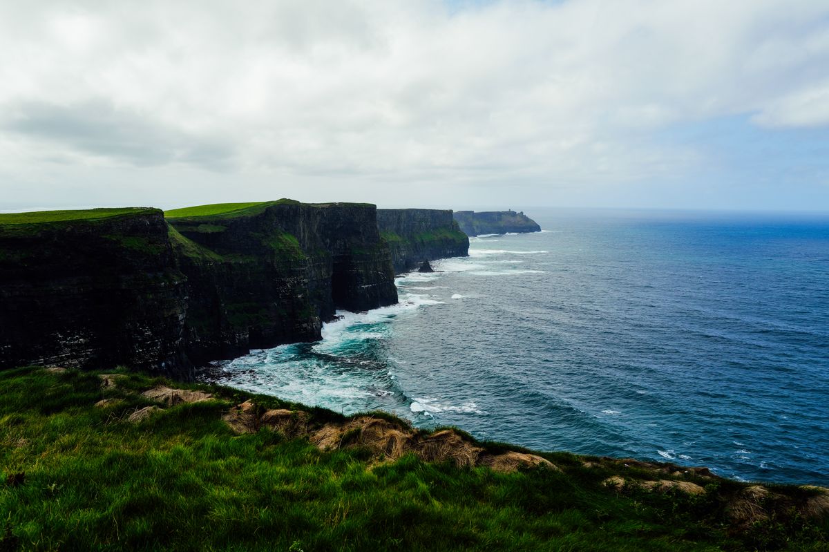 Lush green grass leading to the edge of the Cliffs of Moher with the Atlantic Ocean beyond