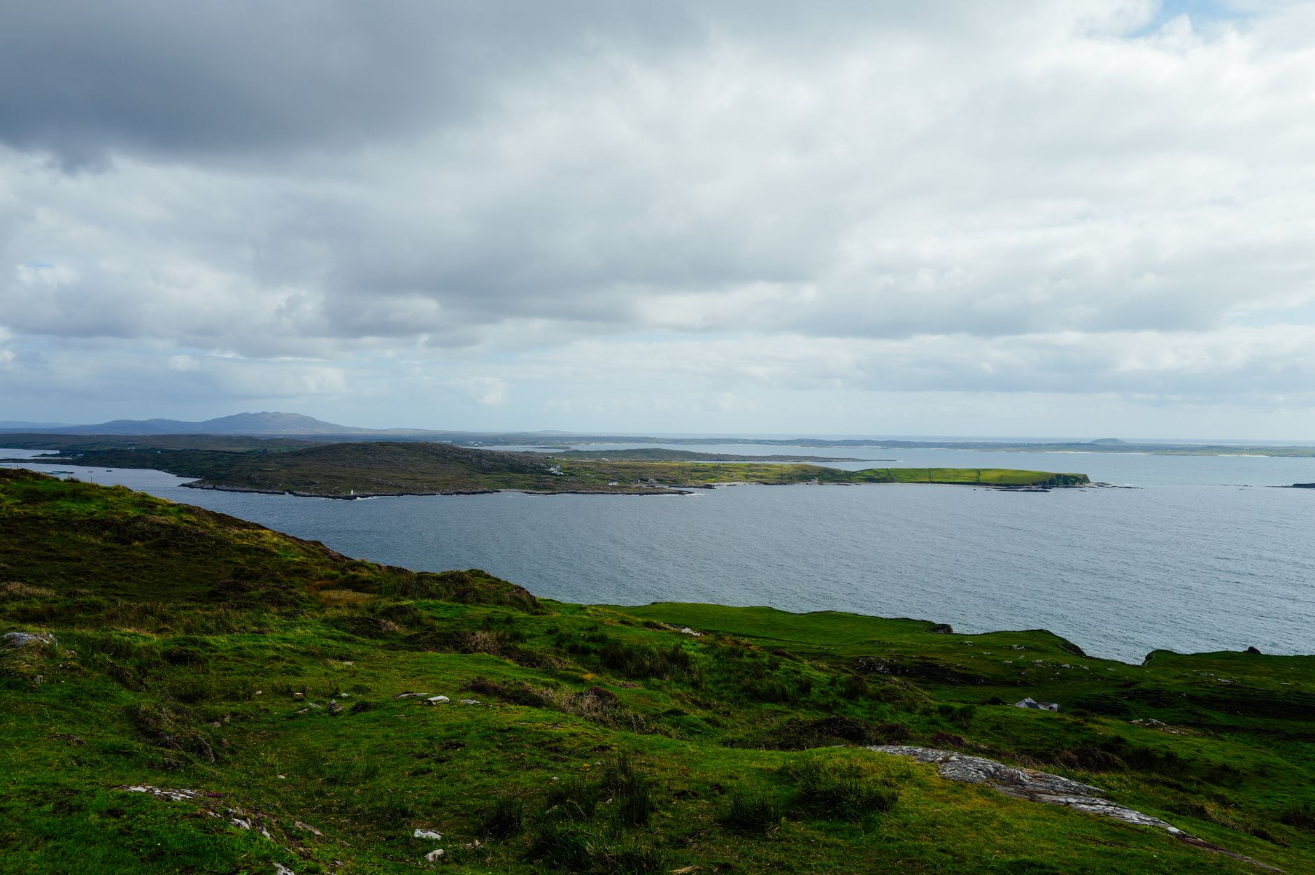 Breathtaking coastal landscape featuring lush green hills and expansive sea views under a cloudy sky.