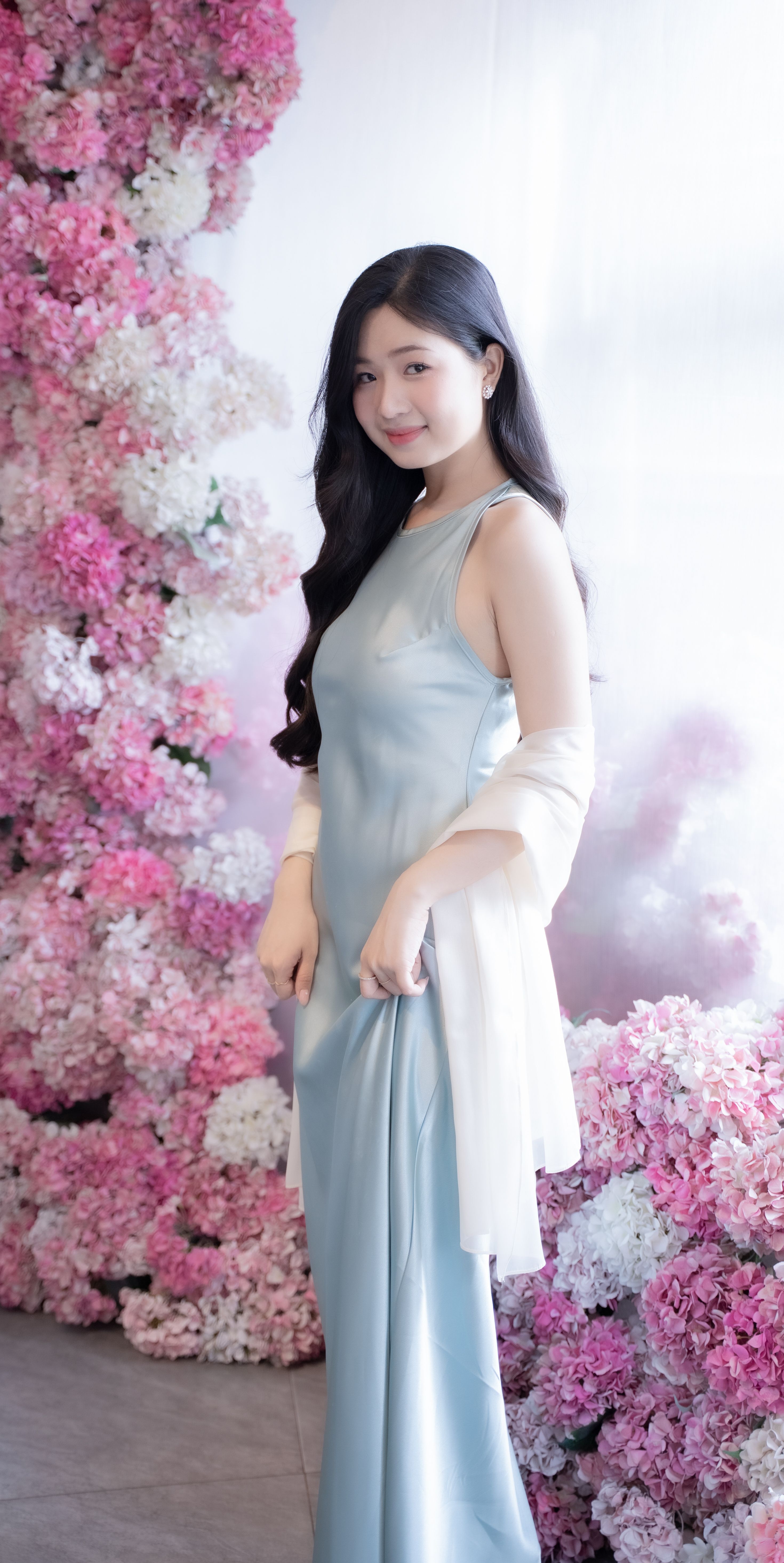 Elegant Woman in Blue Dress with Floral Backdrop · Free Stock Photo