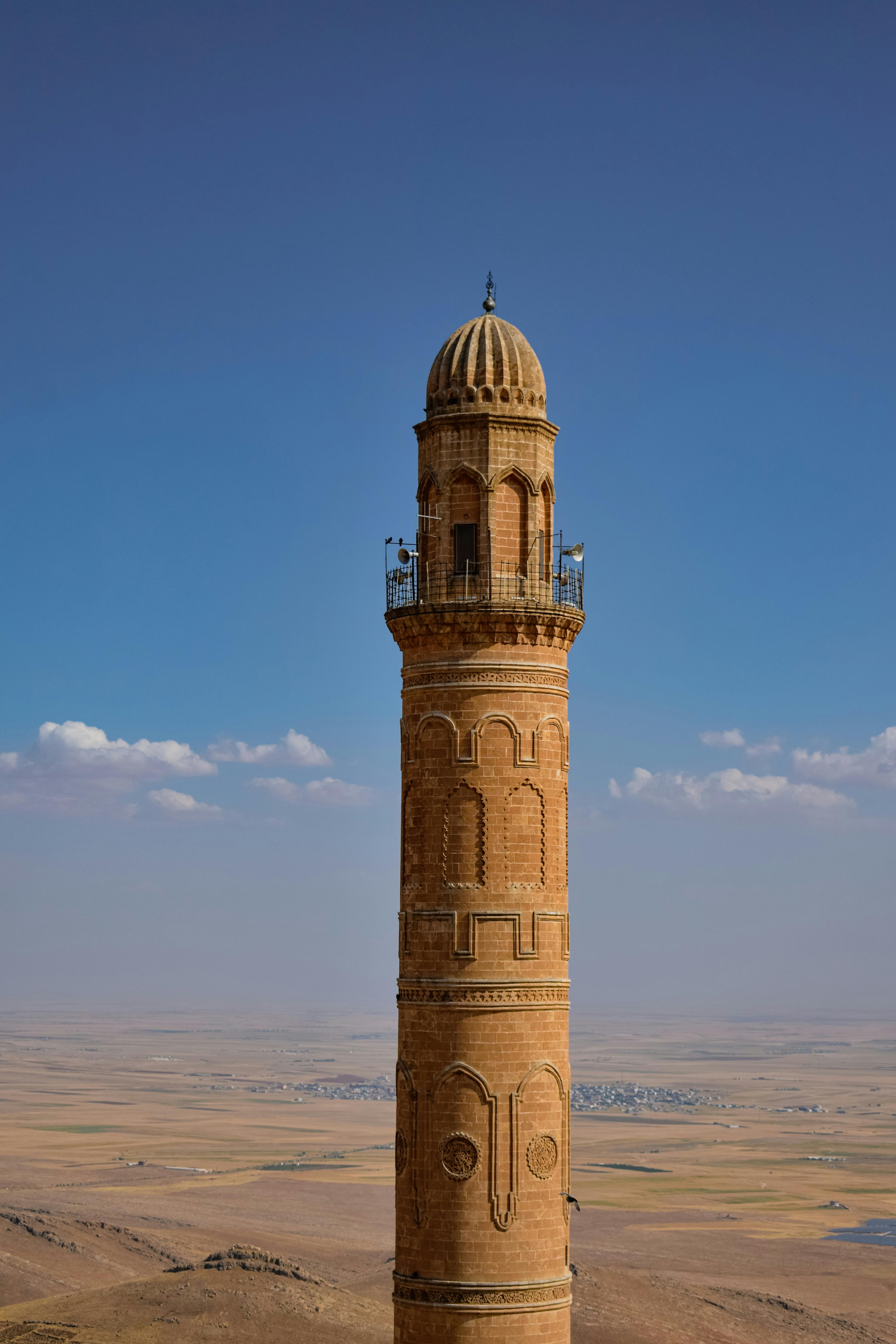 一座历史悠久的砖砌尖塔耸立在蔚蓝的天空下广阔的景观之上