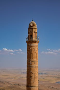 一座历史悠久的砖砌尖塔耸立在蔚蓝的天空下广阔的景观之上