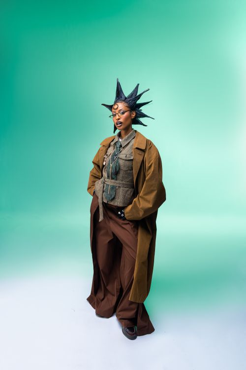 Free Model with spiked hair in unique futuristic fashion against green background. Stock Photo