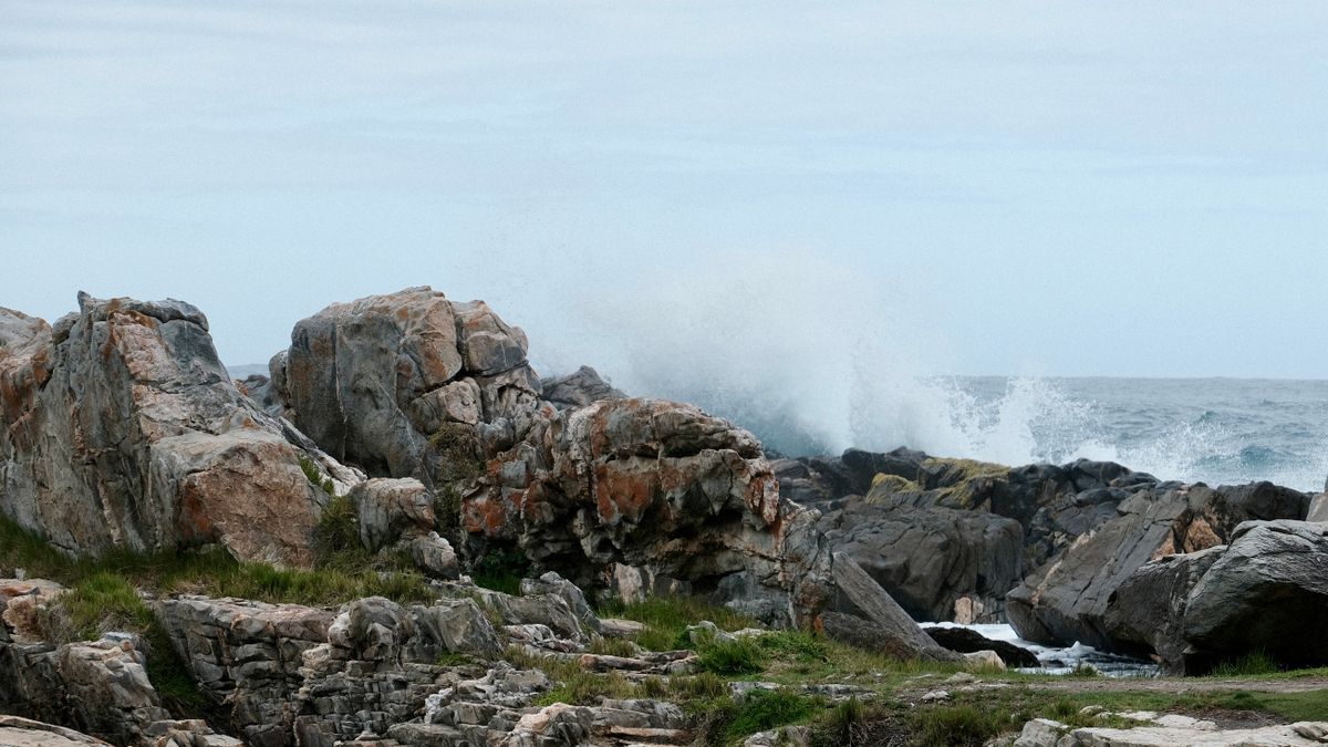 Waves crashing forcefully against rugged coastal rocks, spray flying up