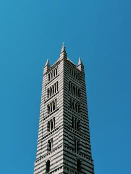 在充满活力的蓝天下，意大利托斯卡纳锡耶纳大教堂塔呈现出美丽的低视角