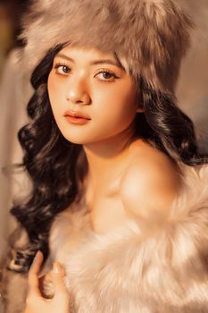 Stylish woman in fur hat and shawl gazing softly, evoking winter elegance and warmth.