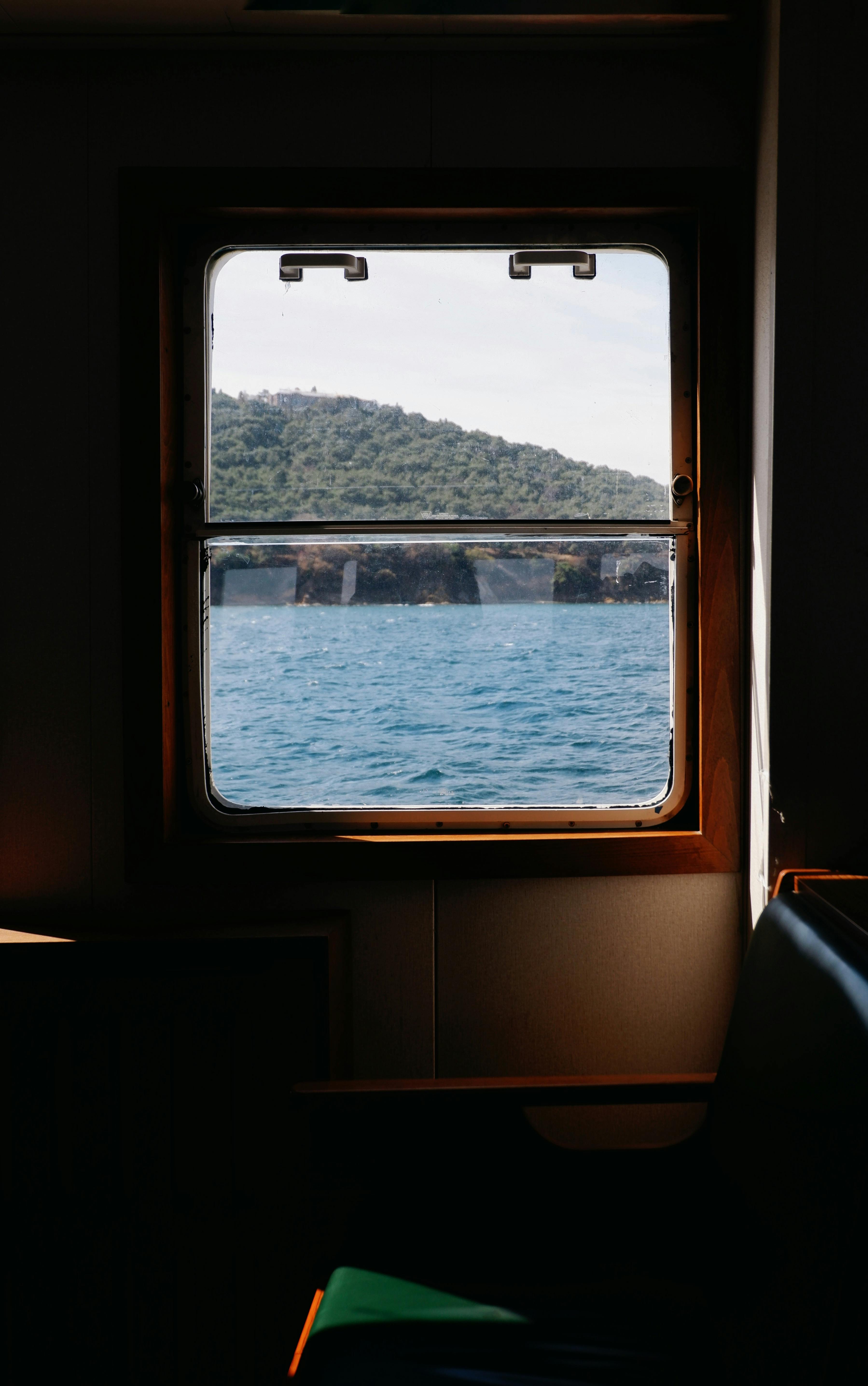 通过船舱的窗户，可以欣赏到海洋和远处山丘的宁静景色
