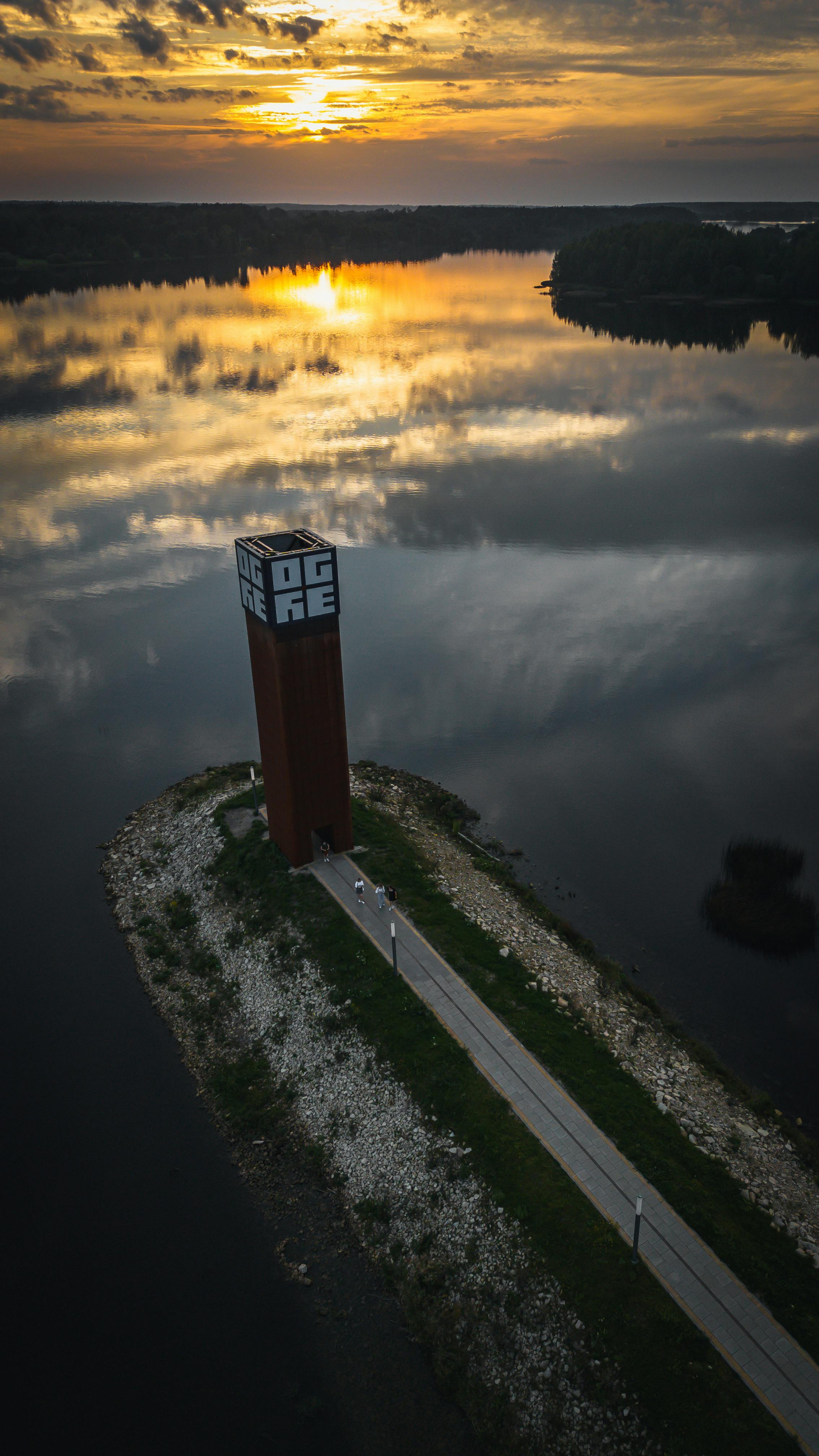 aerial view of lighthouse at sunset over calm lake