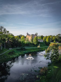 一个风景如画的中世纪城堡，周围环绕着郁郁葱葱的绿色植物和蓝天下的河流