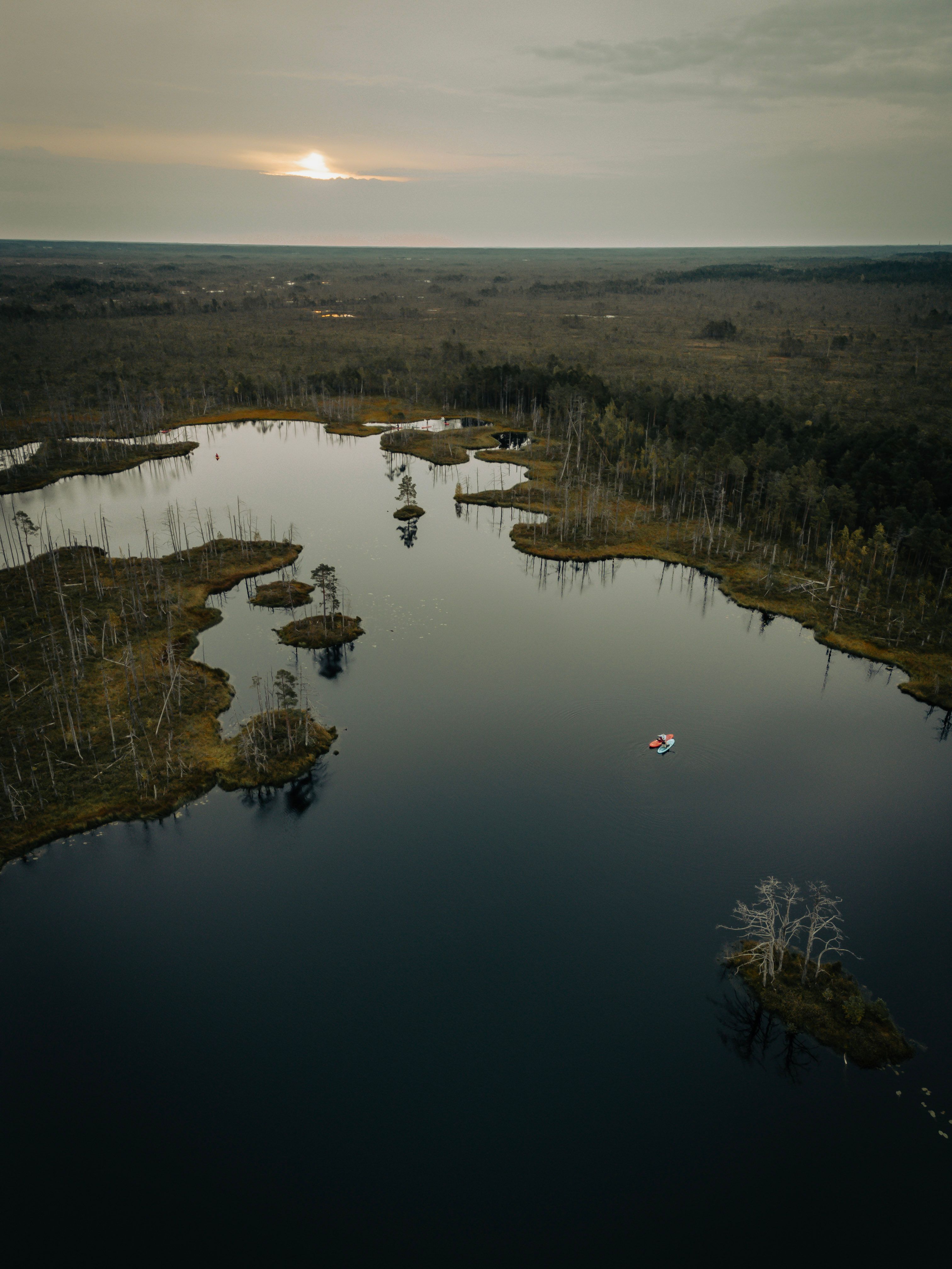 A tranquil aerial shot of a serene lake at sunset with a small boat, offering a sense of calm and natural beauty.