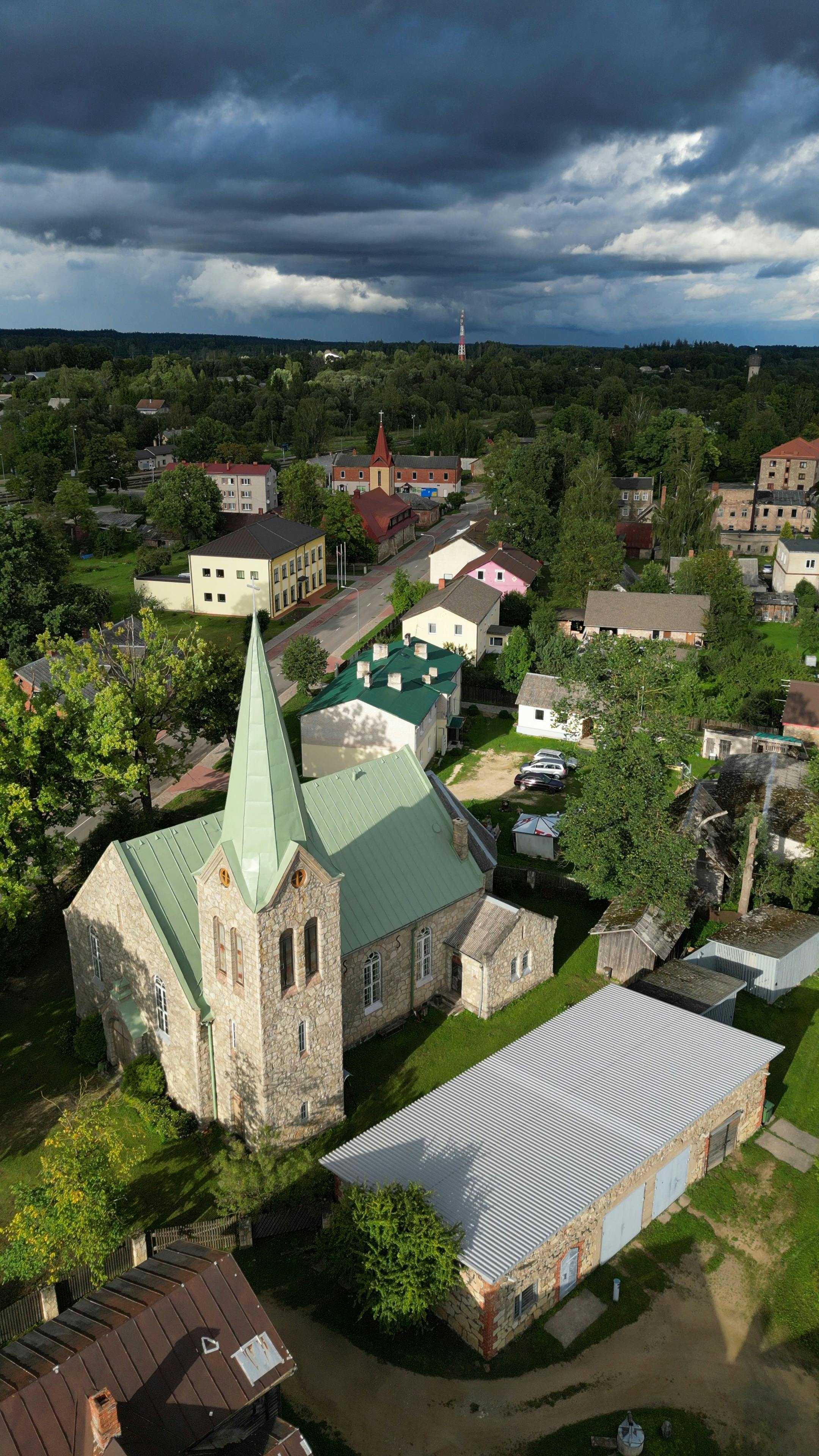Scenic aerial view of a historic church and surrounding townscape under dramatic clouds.