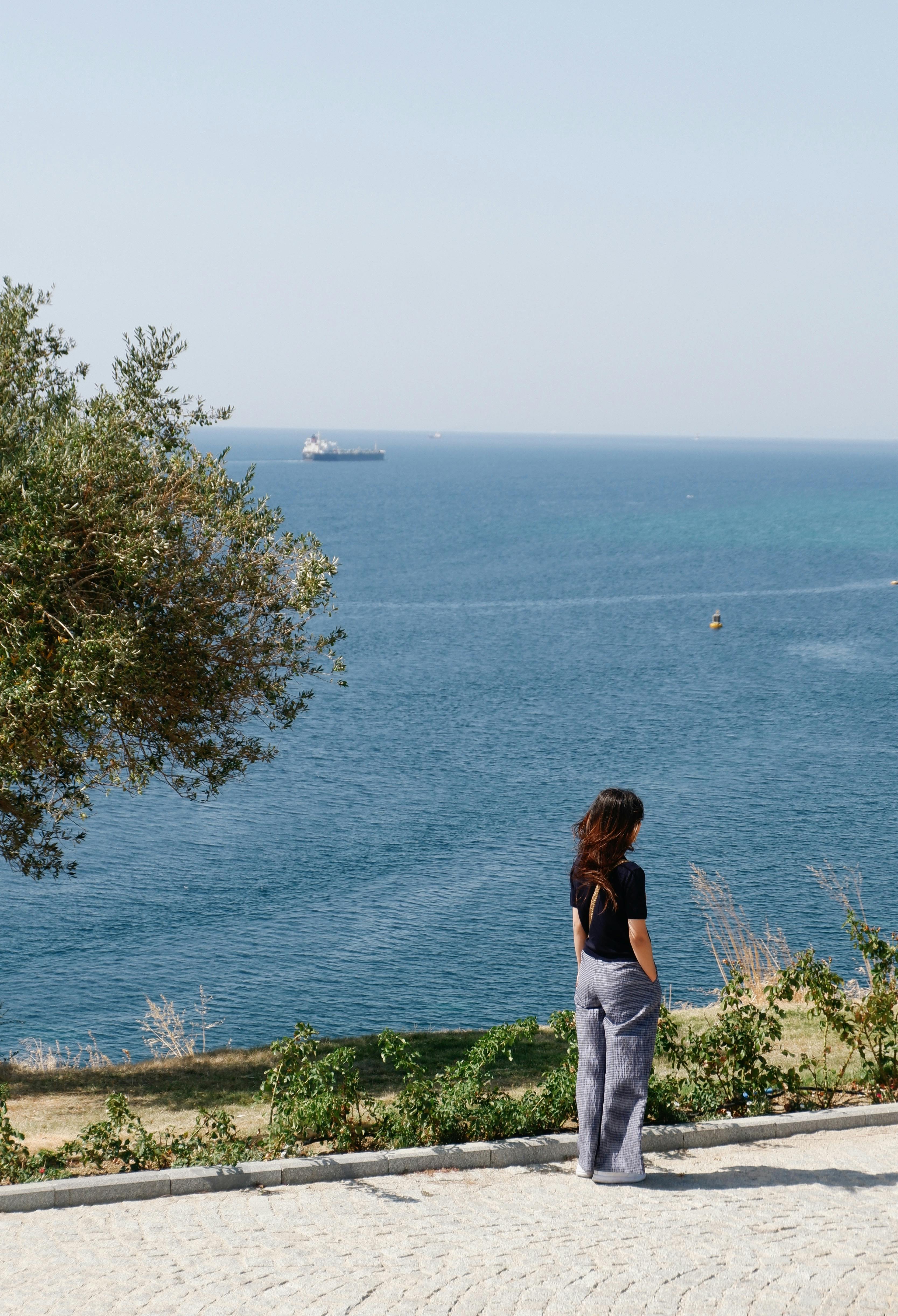 一个女人从容地站在海边，欣赏海天美景