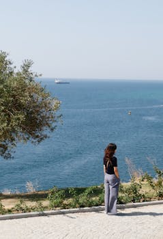 一个女人从容地站在海边，欣赏海天美景