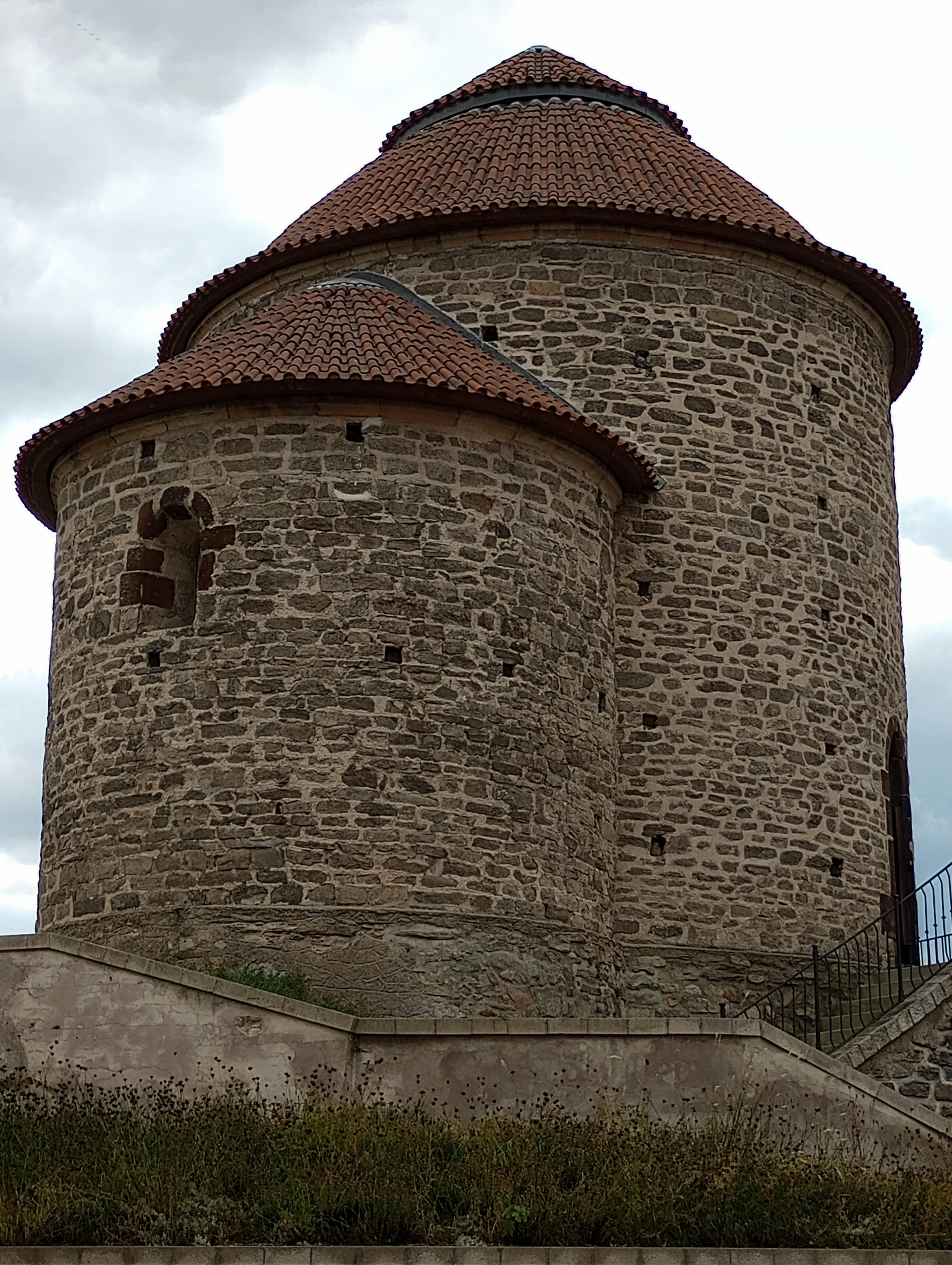 一座罗马式石塔，具有独特的圆形形状和瓷砖屋顶，展示了历史建筑