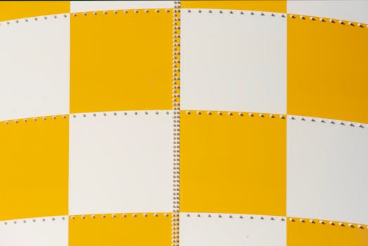 Close-up of a yellow and white checkered metal panel, featuring rows of rivets.